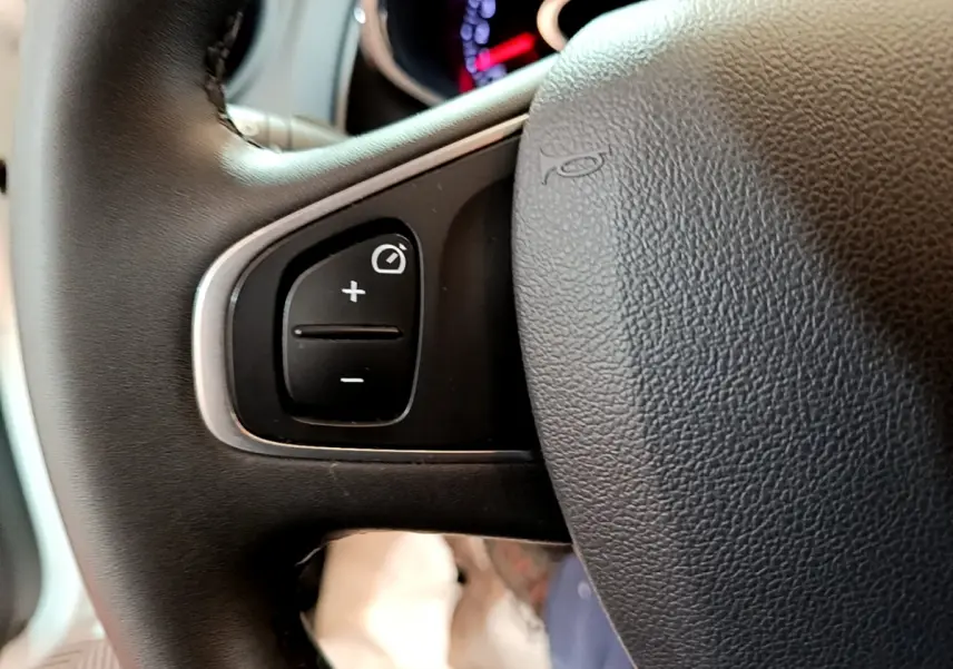 Gros plan sur les commandes de réglage du tableau de bord intégrées au volant cuir noir de la Renault Clio Business TCe 90.