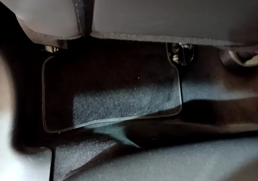 Vue rapprochée du tapis de sol noir sous le siège arrière d'une Renault Clio Business TCe 90 blanche de 2019.