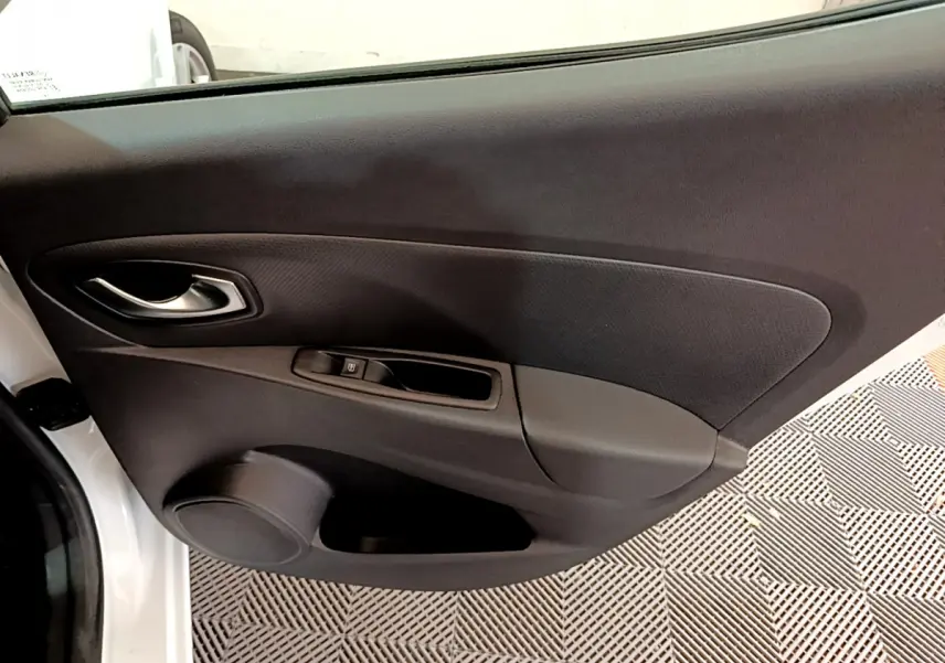 Vue rapprochée de la porte intérieure côté gauche d'une Renault Clio Business TCe 90 blanche, avec poignée argentée et commande de vitre.