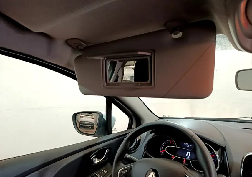 Intérieur Renault Clio Business blanc, vue côté conducteur avec volant cuir et miroir pare-soleil ouvert.