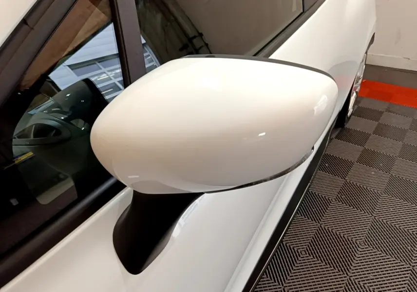 Gros plan sur le rétroviseur côté gauche blanc de la Renault Clio Business TCe 90 blanche, vue partielle du véhicule.