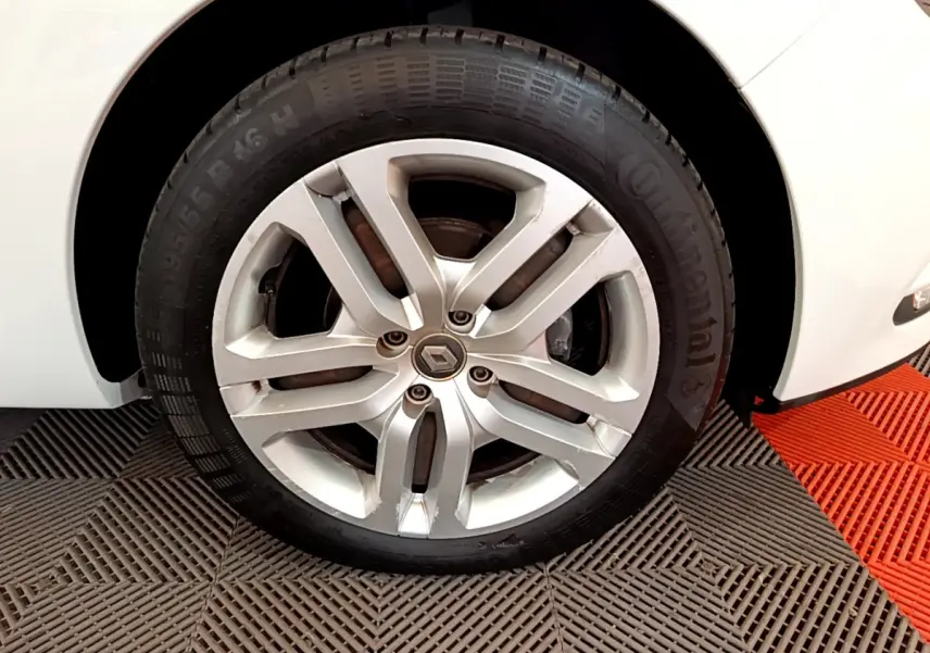 Gros plan sur la roue avant droite d'une Renault Clio Business blanche, jante alliage et pneu Continental visibles.