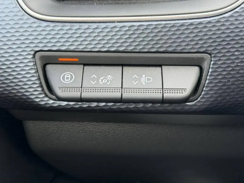 Gros plan sur les boutons de réglage de l’éclairage intérieur et des phares du tableau de bord du Renault Arkana blanc 2025.