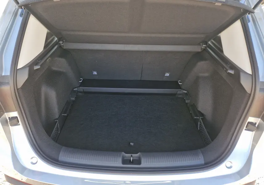 Coffre ouvert vu de l'arrière d'un MG MOTOR 1.5 L Hybrid+ Cosmic Silver, intérieur noir et compartiments latéraux.