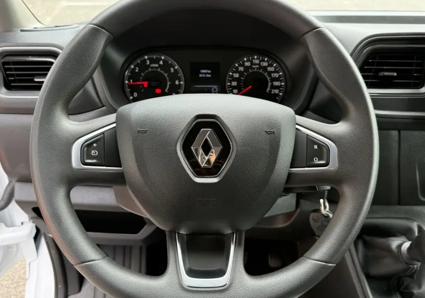 Vue rapprochée du volant noir du Renault Master 2024 avec logo central et tableau de bord en arrière-plan.