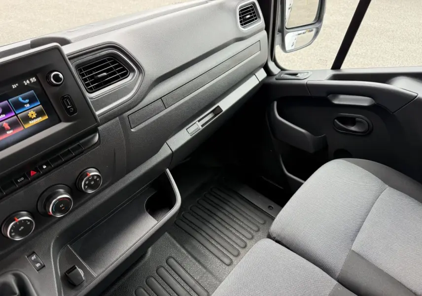 Vue intérieure côté passager du tableau de bord et siège gris du Renault Master 2024, avec écran tactile et commandes climatisation.