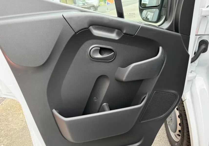 Vue rapprochée de la porte côté conducteur du Renault Master blanc, avec poignée intérieure et haut-parleur intégré.