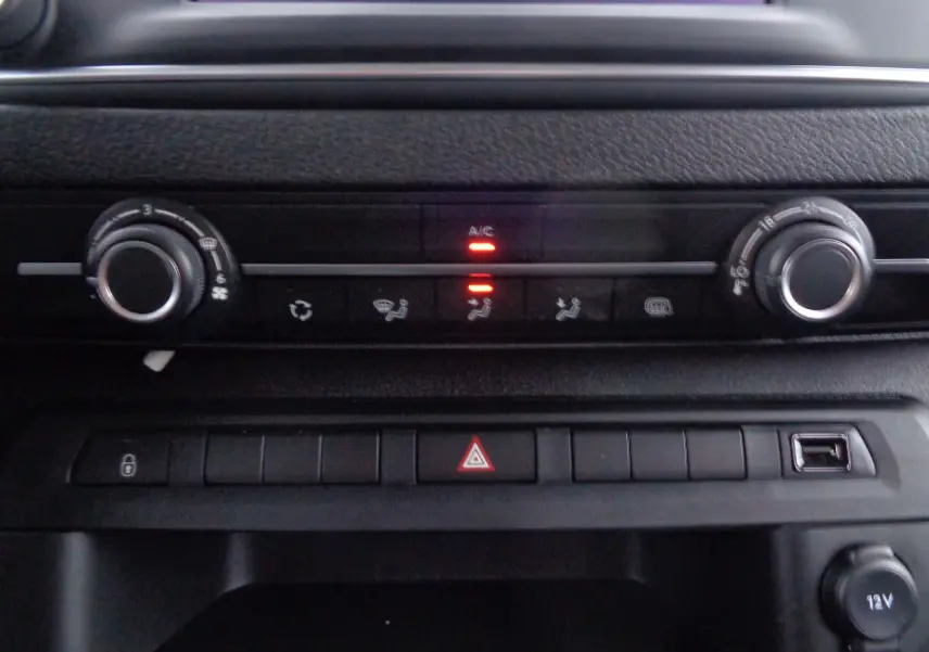 Détail du tableau de bord noir du Peugeot Expert Long 2023 montrant les commandes de climatisation et les boutons de sécurité.
