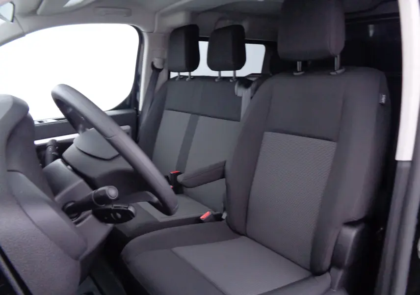 Vue intérieure côté conducteur du Peugeot Expert Long 2023, montrant les sièges noirs en tissu et le volant à gauche.