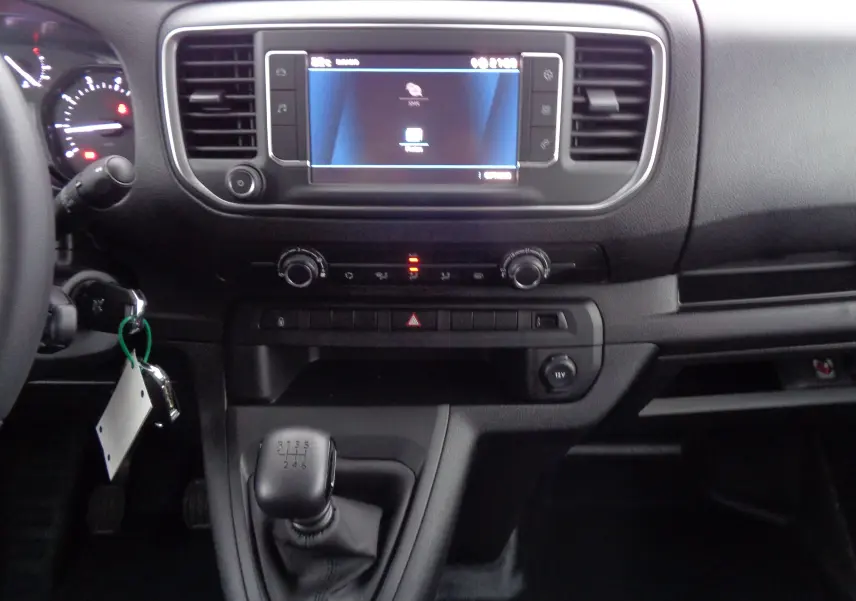 Tableau de bord noir du Peugeot Expert Long 2023 avec écran tactile et levier de vitesse manuel visible au centre.