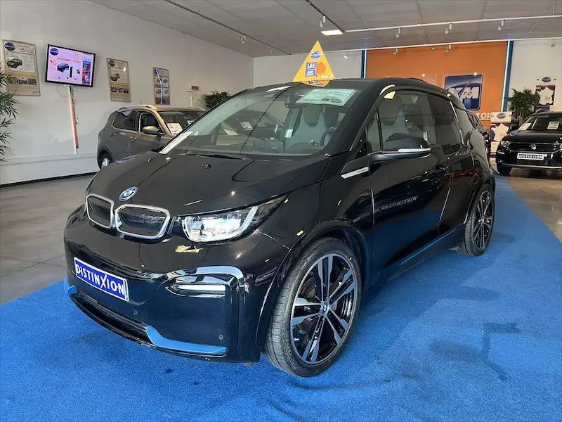 BMW i3 noire vue en 3/4 avant droit, exposée en showroom avec jantes alliage et reflets brillants.