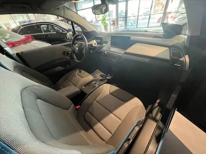 Intérieur de BMW i3 noir 2022 vu côté conducteur, montrant sièges gris bleu et tableau de bord moderne.