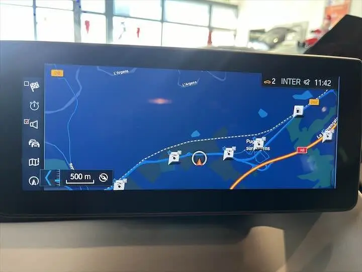 Écran de navigation GPS intégré affichant un itinéraire dans une BMW i3 noire, vue intérieure du tableau de bord.