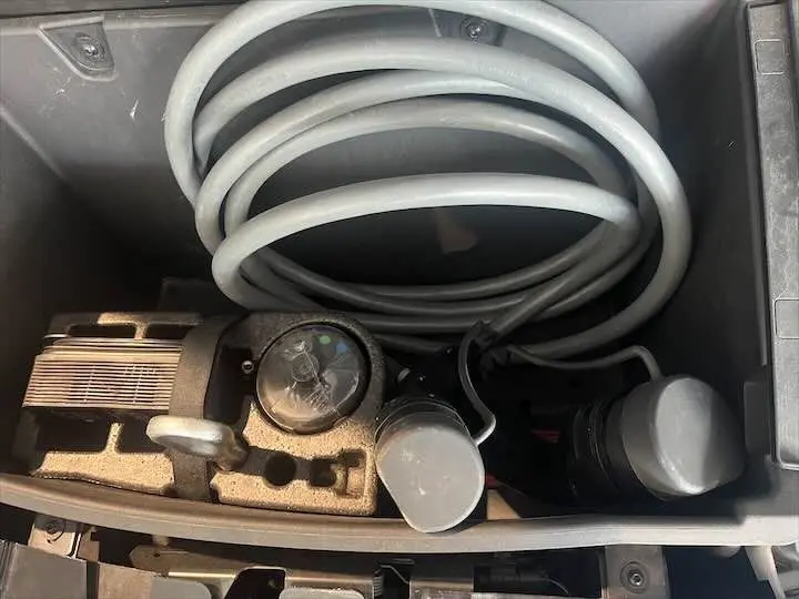 Gros plan sur le câble de recharge électrique blanc enroulé dans le coffre avant d'une BMW i3 noire édition Windmill.