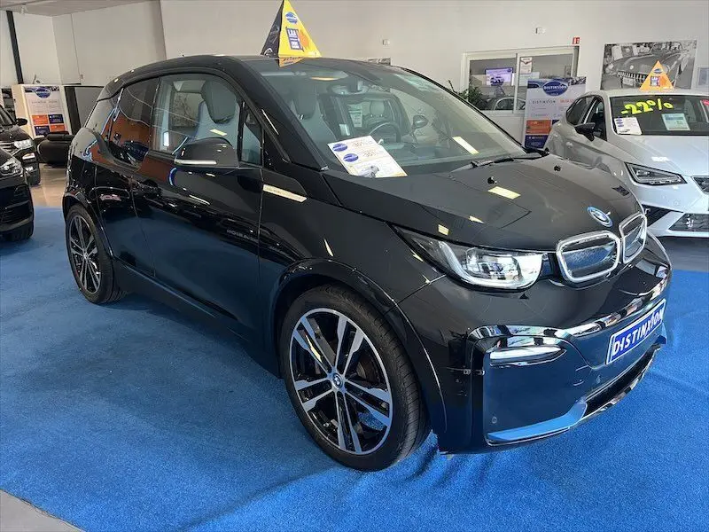 BMW i3 noire vue en 3/4 avant droit dans un showroom, avec jantes sport et intérieur clair visible.