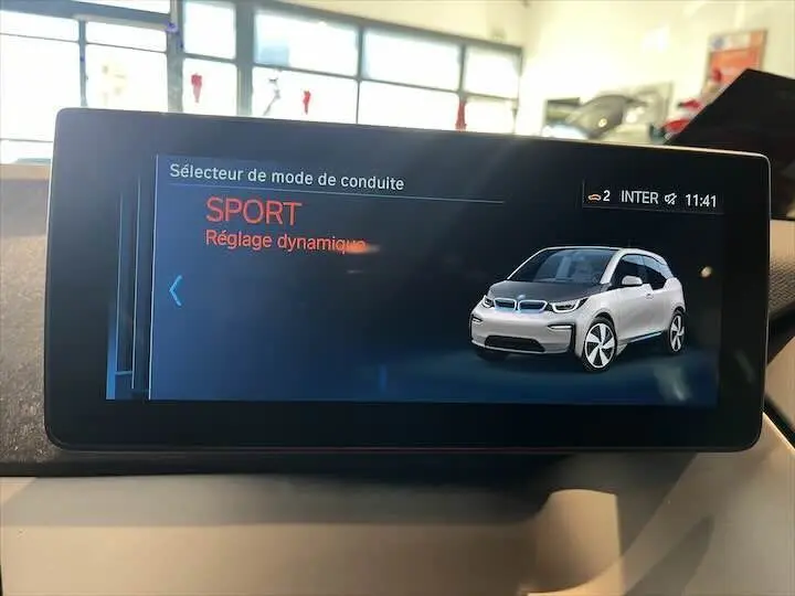 Écran intérieur montrant le mode Sport avec une illustration 3/4 avant d'une BMW i3 blanche.