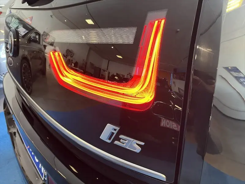 Gros plan sur le feu arrière droit allumé d'une BMW i3 noire, mettant en valeur le logo i3S sur la malle arrière.
