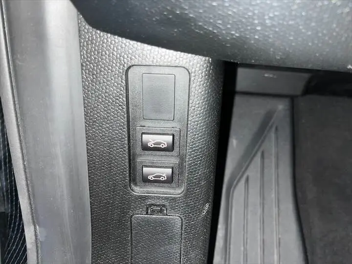 Gros plan sur les boutons d'ouverture du coffre avant et arrière dans l'habitacle d'une BMW i3 noire.