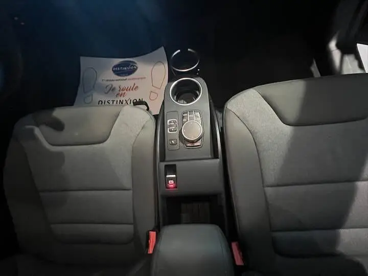 Vue intérieure centrée sur la console centrale et les sièges gris bleu du BMW i3 noir édition Windmill 2022.