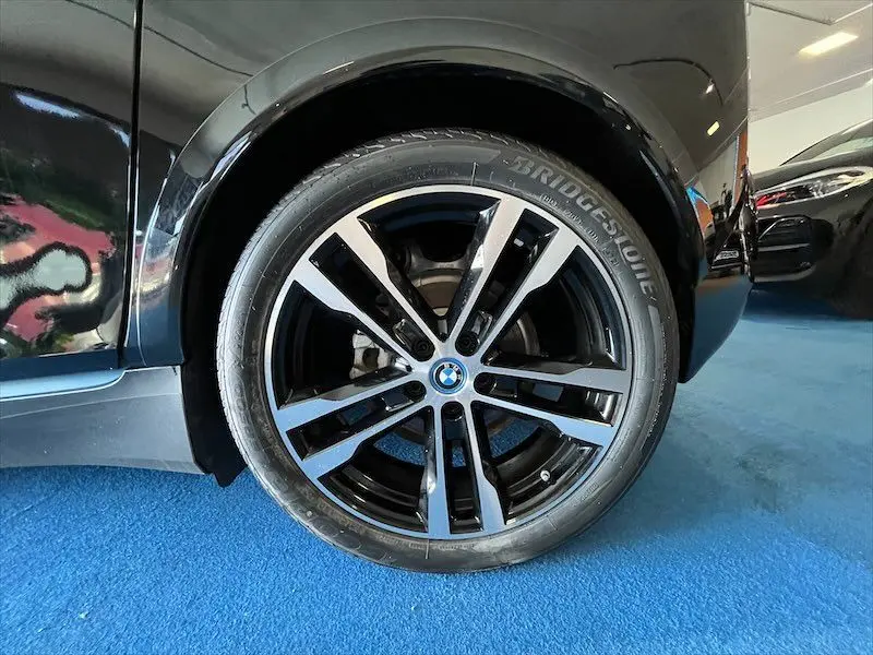 Gros plan sur la roue avant droite noire avec jante BMW bicolore du BMW i3 électrique noir édition Windmill.