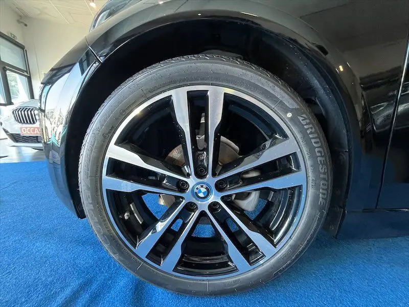 Gros plan sur la jante avant droite noire brillante de la BMW i3 S électrique, avec logo BMW au centre.