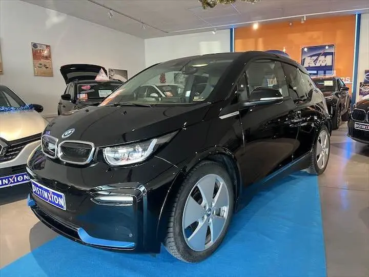 BMW i3 noire vue en 3/4 avant droit dans un showroom, mettant en valeur ses lignes compactes et ses jantes spécifiques.
