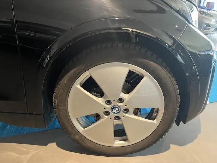 Gros plan sur la roue avant droite avec jante argentée de la BMW i3 noire électrique de 2022.