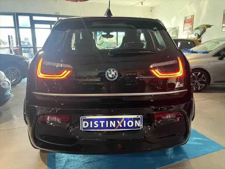 Vue arrière d'une BMW i3 noire avec feux arrière allumés et plaque Distinxion en concession.