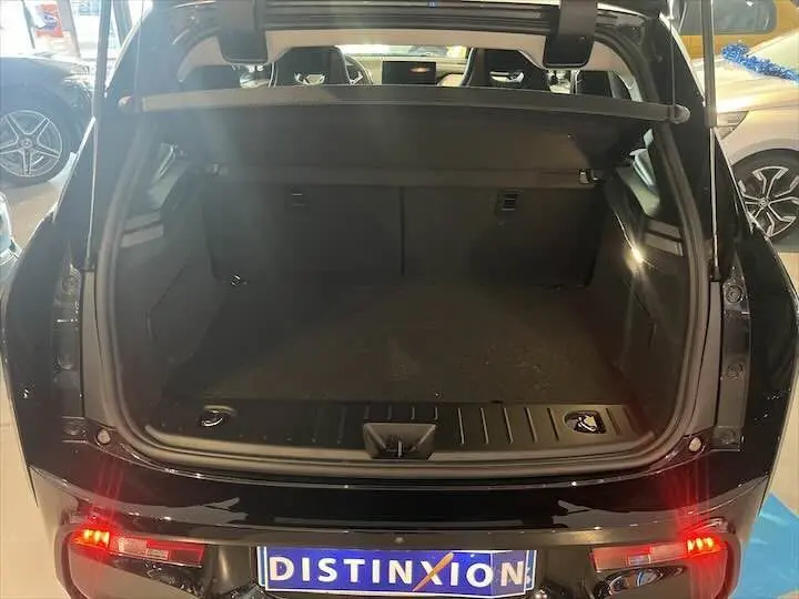 Vue arrière du coffre ouvert d'une BMW i3 noire édition Windmill, avec feux arrière allumés en intérieur showroom.