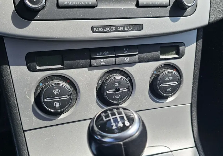 Gros plan sur la console centrale de la Volkswagen Passat 2009, mettant en valeur la commande de climatisation et le levier de vitesse manuel noir.