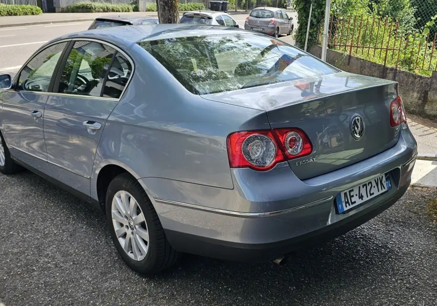 Vue 3/4 arrière droite d'une Volkswagen Passat bleu métallisé de 2009 avec feux arrière ronds et plaques françaises.