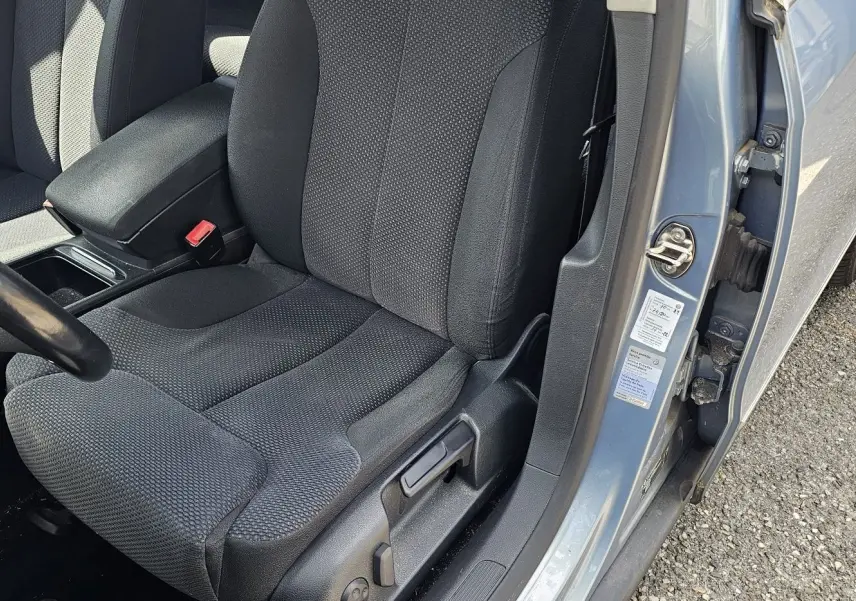 Vue rapprochée du siège conducteur noir et de l'encadrement bleu d'une Volkswagen Passat 2009 avec portière ouverte côté gauche.