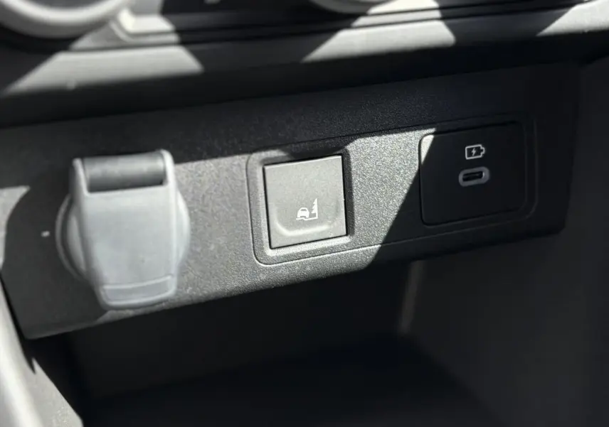 Gros plan sur la console centrale du Dacia Jogger 2025, montrant prises USB et bouton d'aide au maintien en voie.