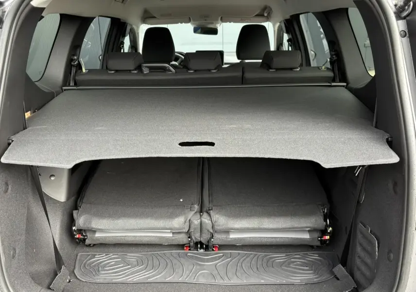 Vue arrière du coffre du Dacia Jogger gris schiste avec sièges rabattus et cache-bagages déployé.