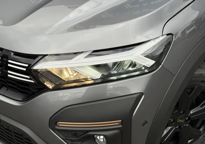 Gros plan sur l'avant droit gris schiste du Dacia Jogger 2025, mettant en valeur le phare LED et la jante noire.