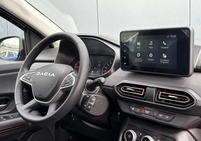 Vue intérieure du tableau de bord du Dacia Jogger gris, avec volant multifonction et écran tactile central 8 pouces.