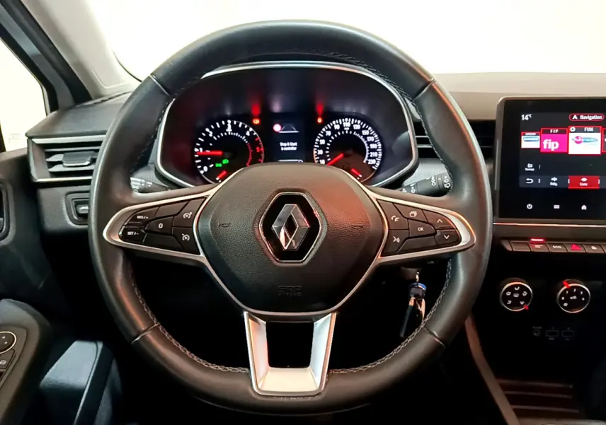 Vue rapprochée du volant cuir noir de la Renault Clio Business avec tableau de bord et écran tactile allumé.