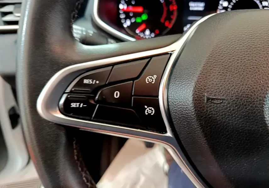 Gros plan sur les commandes noires du régulateur de vitesse à gauche du volant cuir noir de la Renault Clio Business 2020.