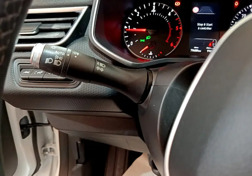 Gros plan sur la manette des phares et clignotants côté gauche du tableau de bord d'une Renault Clio Business Blue dCi blanche de 2020.