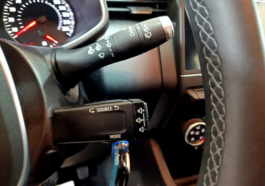 Gros plan sur la commande multimédia et le commodo d'essuie-glace du tableau de bord noir de la Renault Clio Business.