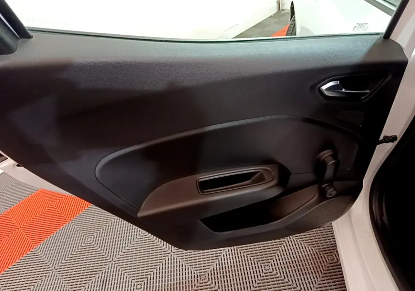 Vue intérieure de la porte côté droit noire d'une Renault Clio Business blanche avec poignée et manivelle de vitre.