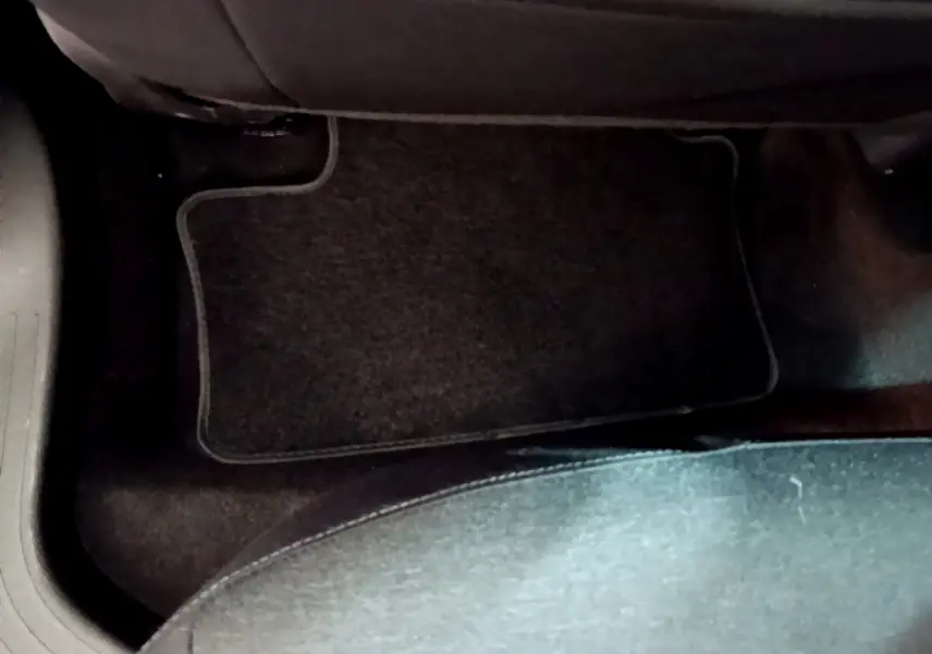 Vue rapprochée du tapis de sol noir côté passager arrière d'une Renault Clio Business blanche de 2020.