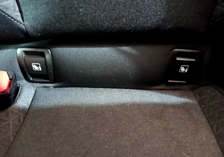 Gros plan sur les commandes de rabattement des sièges arrière noirs de la Renault Clio Business Blue dCi 85 blanche.