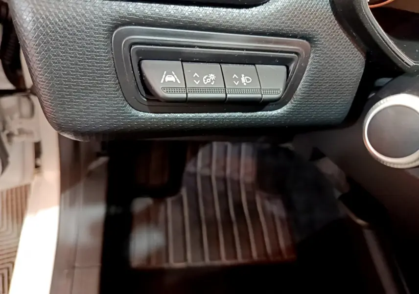 Gros plan sur les commandes d'assistance à la conduite noires dans l'habitacle de la Renault Clio Business Blue dCi 85 blanche.