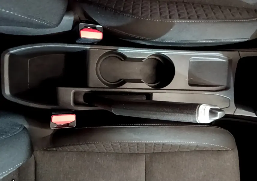 Vue plongeante sur la console centrale noire de la Renault Clio Business Blue dCi 85 avec frein à main et porte-gobelets.