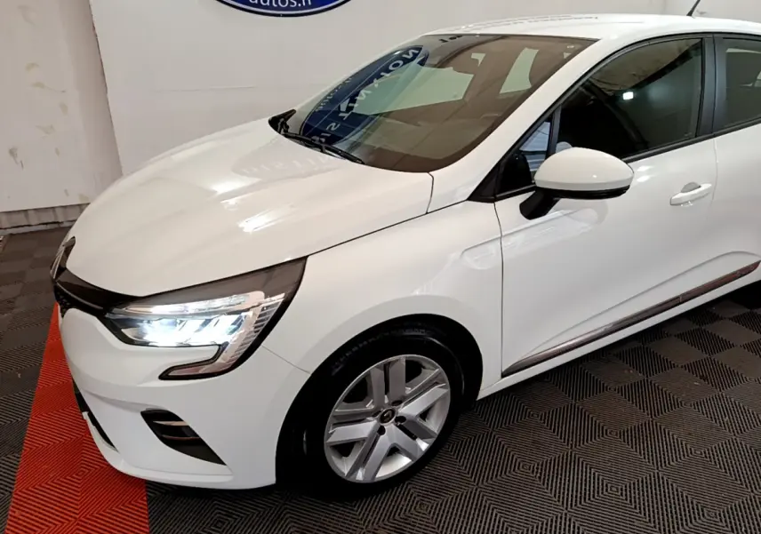 Vue 3/4 avant droit d'une Renault Clio Business Blue dCi 85 blanche avec phares LED allumés et jantes alliage.