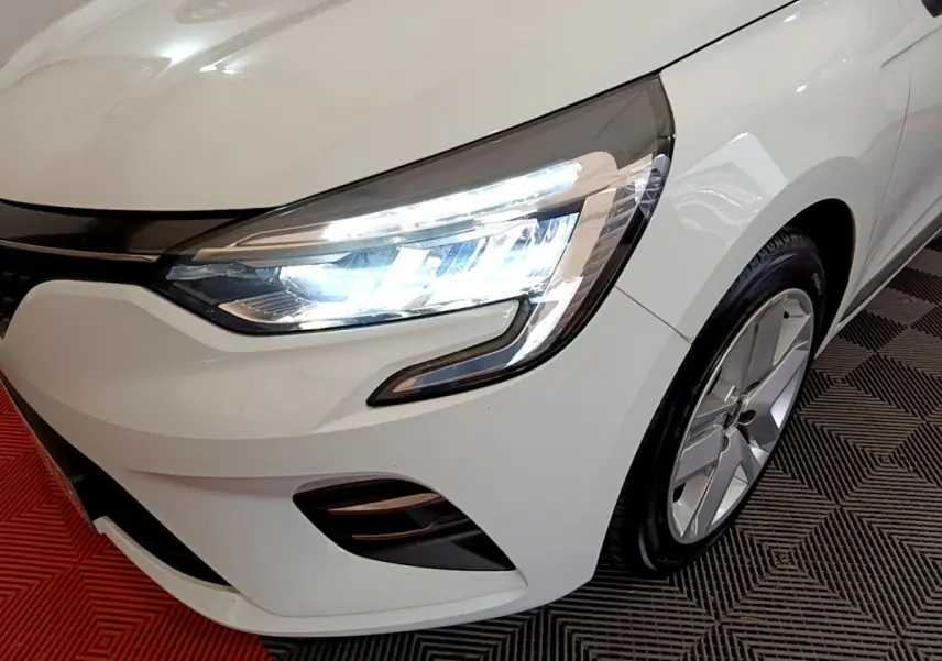 Gros plan sur l'avant droit blanc d'une Renault Clio 2020 Business Blue dCi avec phares LED allumés et jante alliage.