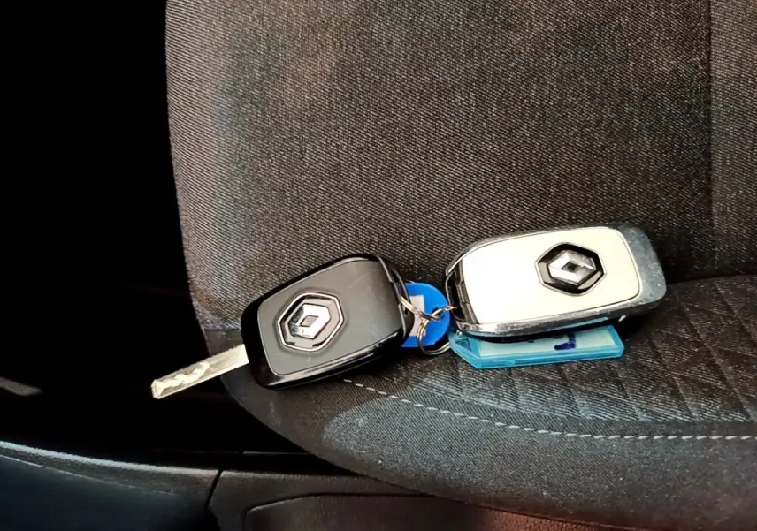 Clé noire et clé blanche Renault posées sur un siège tissu gris foncé à l'intérieur du véhicule.