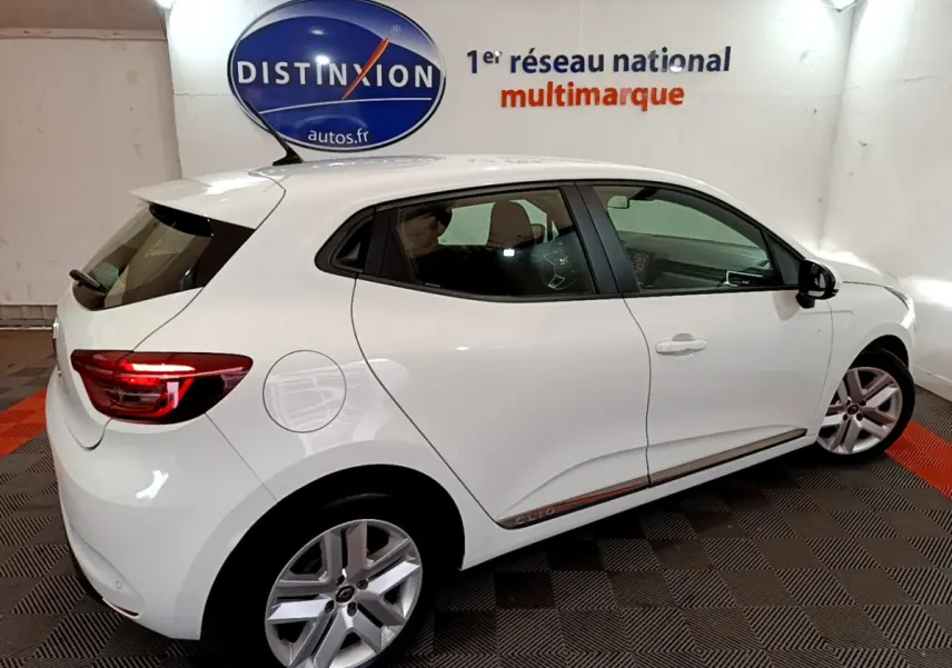 Vue de profil côté gauche d'une Renault Clio Business Blue dCi 85 blanche avec jantes alliage et feux arrière allumés.