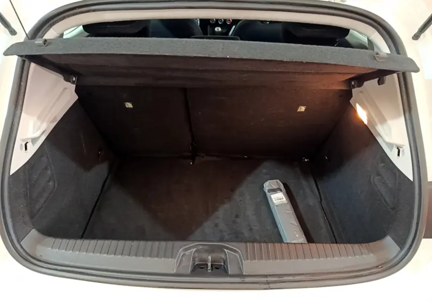 Coffre ouvert d'une Renault Clio Business Blue dCi 85 blanche, vue arrière montrant l'espace de chargement vide avec une petite trousse.